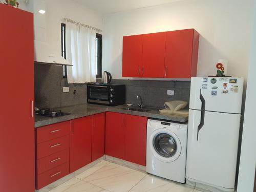 a kitchen with red cabinets and a washing machine at Coqueto departamento in Puerto Iguazú