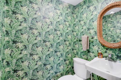 een badkamer met groen behang, een toilet en een spiegel bij Paradise View House in Marathon