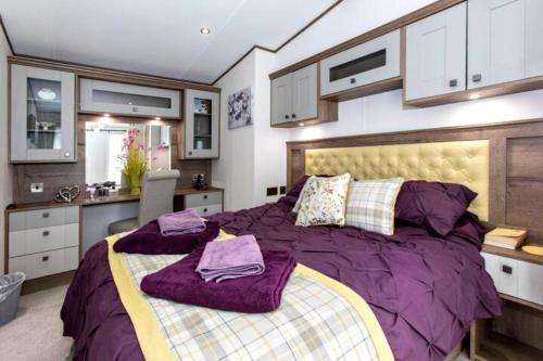 a bedroom with a large bed with purple comforter at Silver Birches in Wisbech