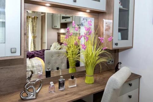 a bathroom with a vanity with flowers and a mirror at Silver Birches in Wisbech