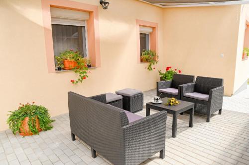 a patio with chairs and tables and flowers at Bazaltorgona Apartman in Kisapáti