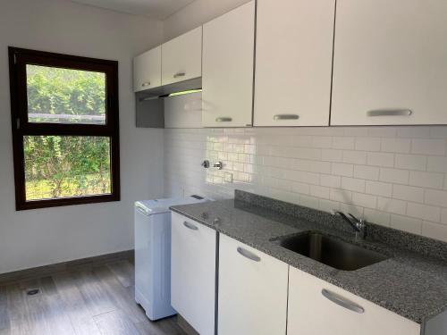 a kitchen with white cabinets and a sink and a window at Acogedora y amplia casa en Salta! in Salta