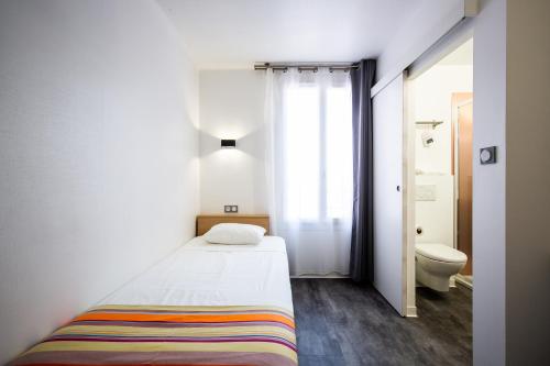 a small bedroom with a bed and a toilet at Hôtel PB - Paris-Barcelone in Perpignan