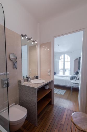 une salle de bain avec un lavabo, des toilettes et un miroir dans l'établissement Bel appartement bourgeois au centre-ville de Biarritz, à Biarritz