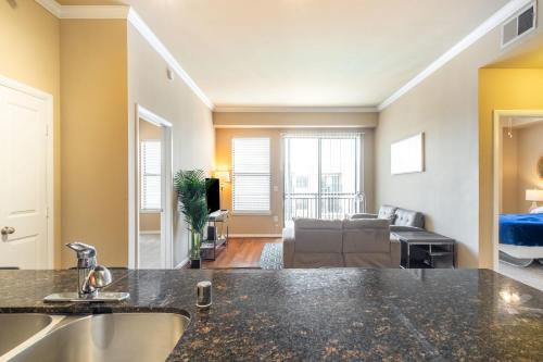 a kitchen with a sink and a living room at 2BR Executive Suite With Pool, Gym and Fast Wi-Fi By ENVITAE in Dallas