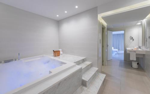 a white bathroom with a large tub and a sink at Royal Azur Thalassa in Hammamet