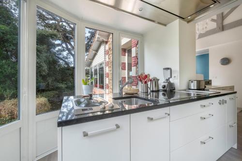une cuisine avec des placards blancs et une grande fenêtre dans l'établissement Villa balnéaire pour 8 - 75m de la plage, à Pornichet