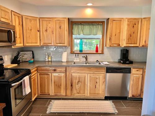 a kitchen with wooden cabinets and a sink at THE GREEN HOUSE - New River Gorge National Park in Lansing