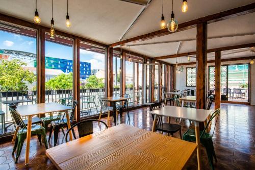 a restaurant with wooden tables and chairs and windows at Hôtel PB - Paris-Barcelone in Perpignan