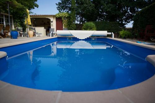 una piscina con silla y agua azul en La Soleillade Laudun, en Laudun