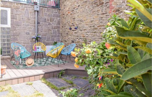 a patio with chairs and flowers and a brick wall at 5 Bedroom Cozy Home In Lézardrieux in Lézardrieux