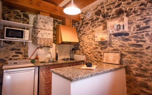 a kitchen with a stone wall and a counter top at Apartamento duplex rural con chimenea y vistas panorámicas desde la cama in San Martín Sacalm