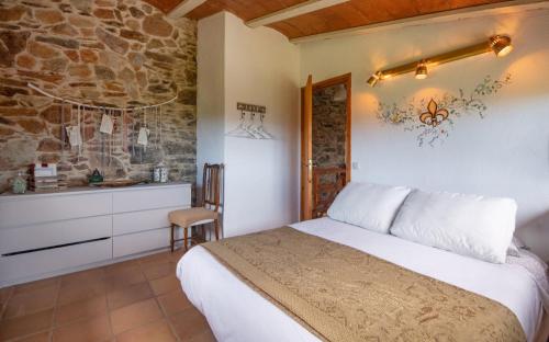 - une chambre avec un lit et un mur en pierre dans l'établissement Apartamento duplex rural con chimenea y vistas panorámicas desde la cama, à San Martín Sacalm