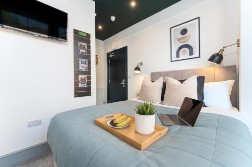 a bed with a tray with a laptop on it at The Madison - Premium Self Check-In Studios & Apartments in Southampton