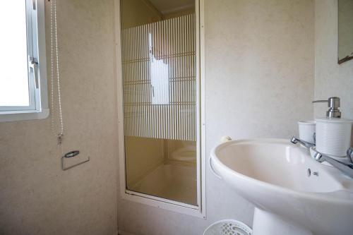 a bathroom with a sink and a glass shower at 6 Berth Caravan For Hire At Martello Beach Holiday Park In Essex Ref 29017y in Clacton-on-Sea
