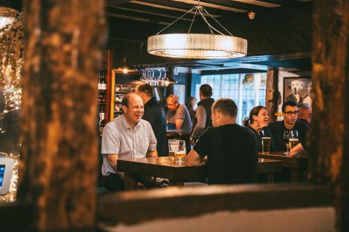 um grupo de pessoas sentadas em mesas em um bar em Rose & Crown Inn em Knutsford