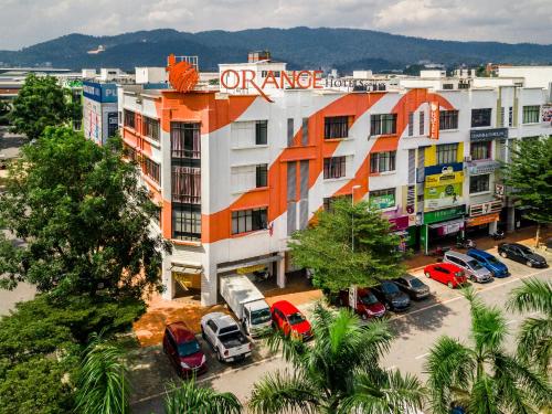 an apartment building with cars parked in a parking lot at 1 Orange Hotel Sungai Buloh in Sungai Buluh