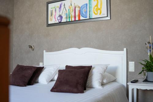 a white bed with pillows and a picture on the wall at Hôtel Picardia in Saint-Valery-sur-Somme