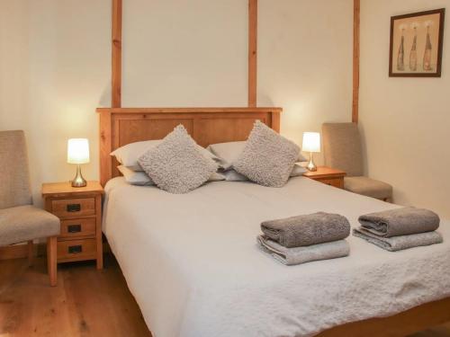 1 dormitorio con 1 cama blanca con 2 sillas y 2 lámparas en Acksea Holiday Lodges, en Kinnerley