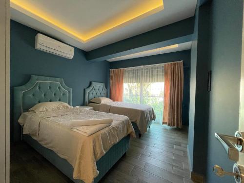 two beds in a room with blue walls and a window at X SUITE APART in Fethiye