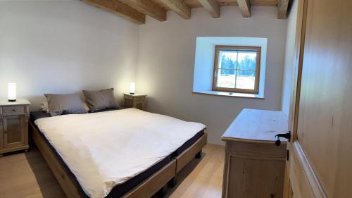 um pequeno quarto com uma cama e uma janela em Brasel em La Brévine