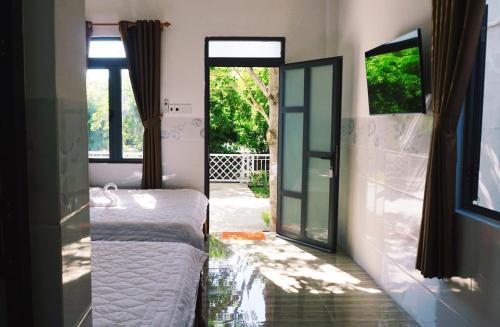 1 dormitorio con 1 cama y puerta corredera de cristal en Hải An Homestay - Garden by the Beach en Phan Rang