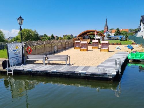 a dock with benches and chairs on the water at PENSJONAT SUNRISE nad rozlewiskiem Delty Świny in Świnoujście