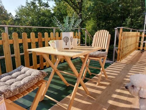 una mesa de madera y sillas en una terraza con un perro en Apartman Vrganj, en Savinac
