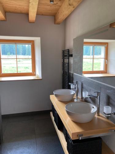 a bathroom with two sinks and two windows at Brasel in La Brévine