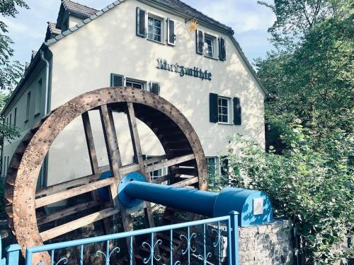 a building with a water wheel in front of it at Apartment im Gästehaus Matzmühle Ruhland (6-8 P.) in Ruhland