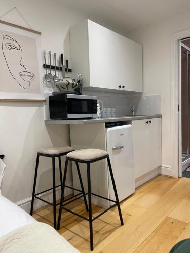 a kitchen with two bar stools and a microwave at The Hideaway in Kent