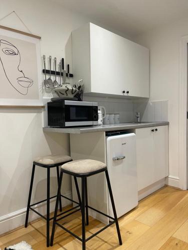 uma cozinha com um balcão com 2 bancos e um micro-ondas em The Hideaway em Kent