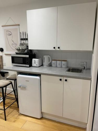 a kitchen with white cabinets and a white refrigerator at The Hideaway in Kent