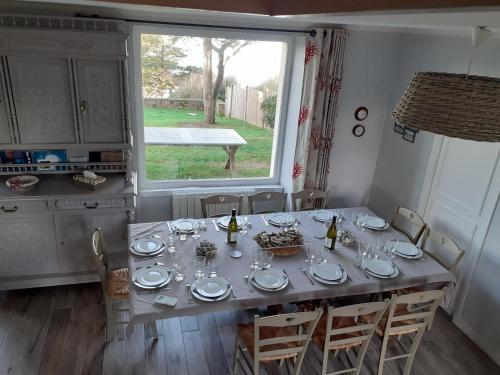 - une table à manger avec des assiettes et des verres à vin dans l'établissement Maison vue exeptionnelle sur la mer, à Lancieux