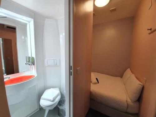 a small bathroom with a bed and a sink at easyHotel Victoria in London