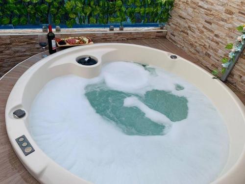 a bath tub filled with water with a bunch ofilage at Romantic Studio w/Jacuzzi 15 min Airport in Ensanche Los Minas