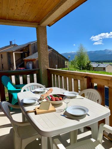 une table et des chaises blanches sur une terrasse avec une table et des chaises dans l'établissement Lou Castelou - T3 Cosy - Chromecast TV, aux Angles