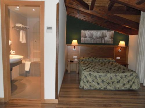 1 dormitorio con 1 cama y baño con lavamanos en Hotel Milagros Rio Riaza, en Milagros
