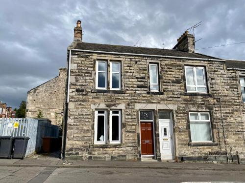 an old brick house with a red door at 4B Millhill Street in Dunfermline