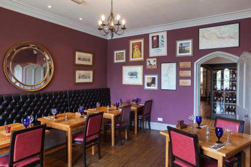 a restaurant with wooden tables and chairs and a purple wall at The Corner House Hotel in Taunton