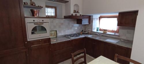 La cuisine est équipée de placards en bois et d'une cuisinière blanche. dans l'établissement Appartamento Tzendelabo, à Gaby