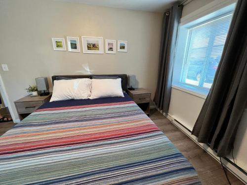 a bedroom with a bed with a striped blanket and a window at Burrel Avenue Apartments in Cooperstown