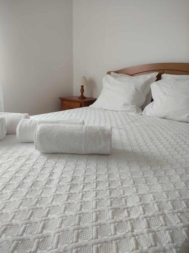 a white bed with white sheets and pillows at Quinta dos Brazilaves - Ponte de Lima in Ponte de Lima