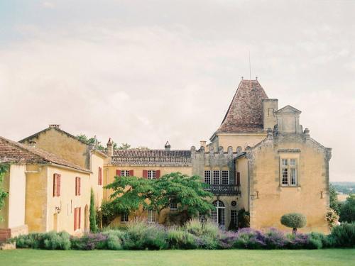 une vieille maison dans une cour fleurie dans l'établissement Gîtes du Château Mont d'Onel, à Couze-et-Saint-Front