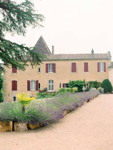 une grande maison avec des fleurs violettes en face dans l'établissement Gîtes du Château Mont d'Onel, à Couze-et-Saint-Front
