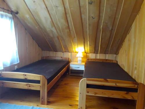 two beds in a room with a wooden ceiling at Zakątek nad Sanem, Załuż 128 in Załuż