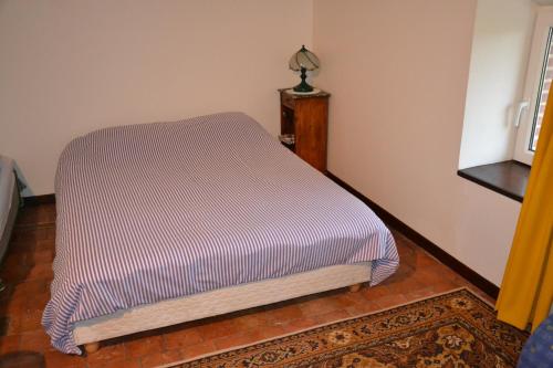 a bed in a room with a striped blanket at Chambres D'hotes Beaupel in Neuvy-en-Mauges