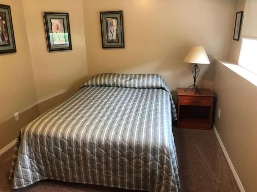 1 dormitorio con 1 cama y mesita de noche con lámpara en Paradise Canyon Golf Resort, Luxury Condo M407, en Lethbridge