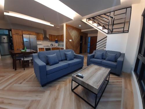 uma sala de estar com dois sofás azuis e uma mesa em Winch House em Pili