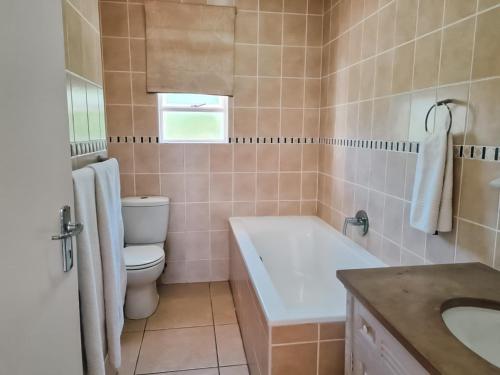 a bathroom with a tub and a toilet and a sink at Villa 44, The Estuary Country Estate, Port Edward in Port Edward